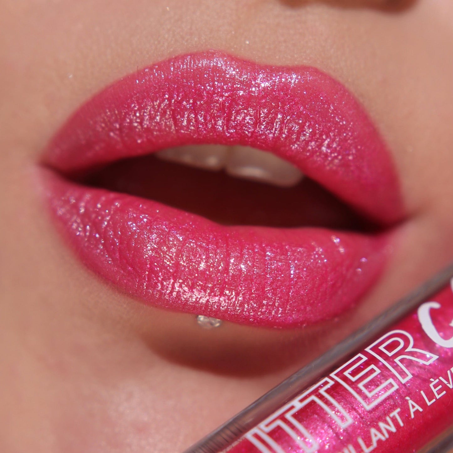 A close up of a models lips wearing the glitter gloss in he shade Fuchsia.