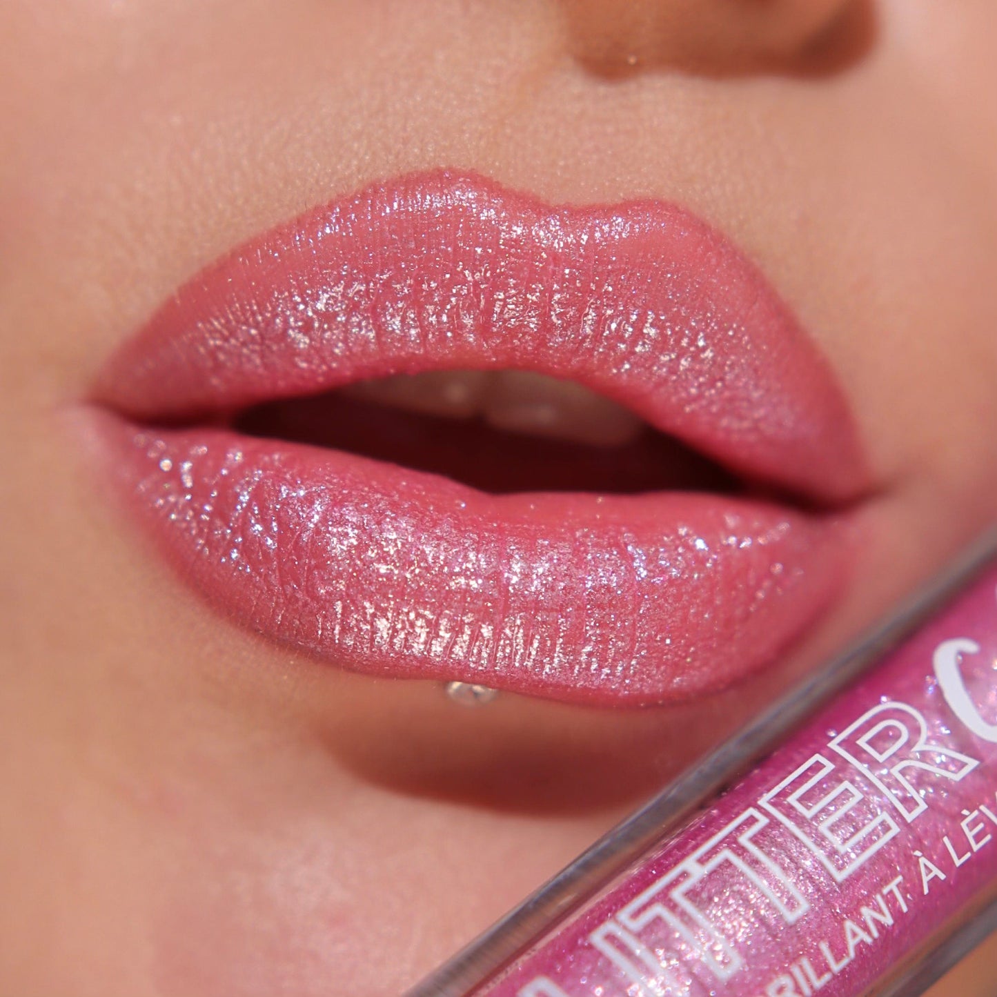 A close up of a models lips wearing the glitter gloss in he shade Bright Pink.