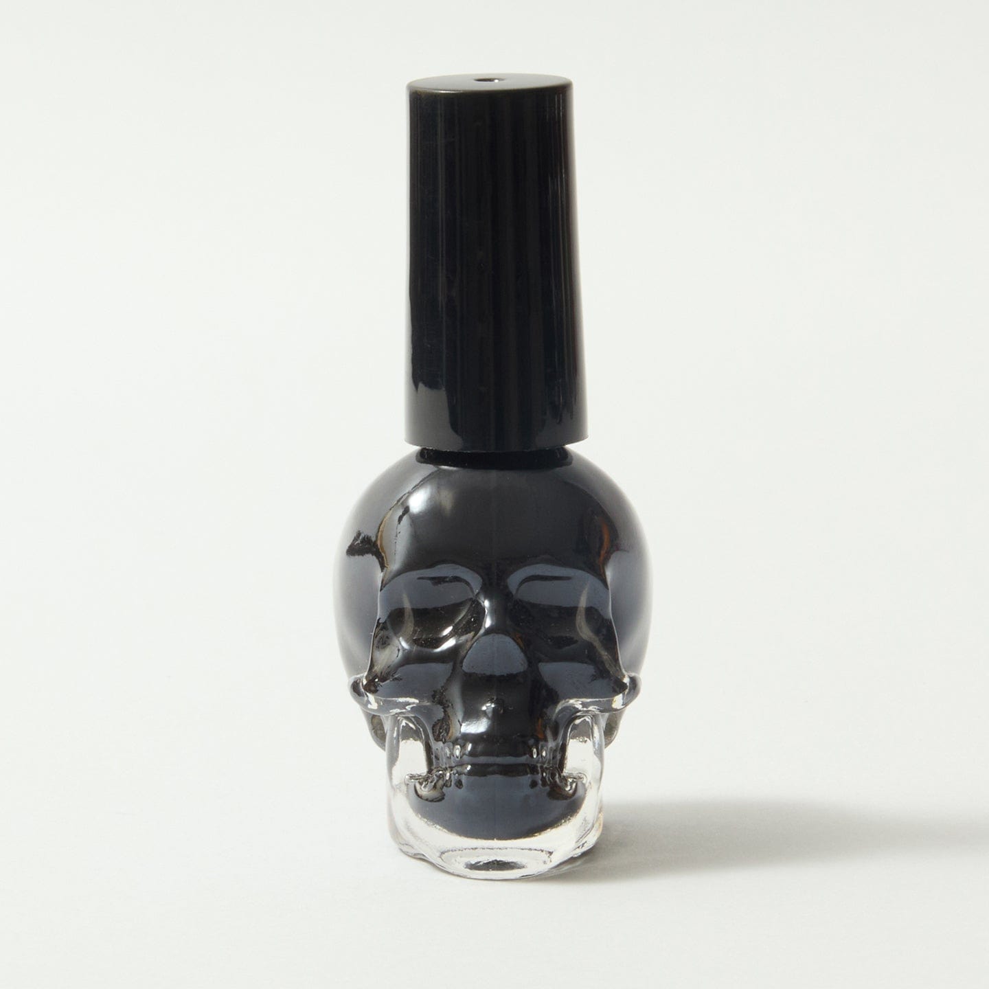 Gothica black nail varnish in a skull bottle, on a white background.