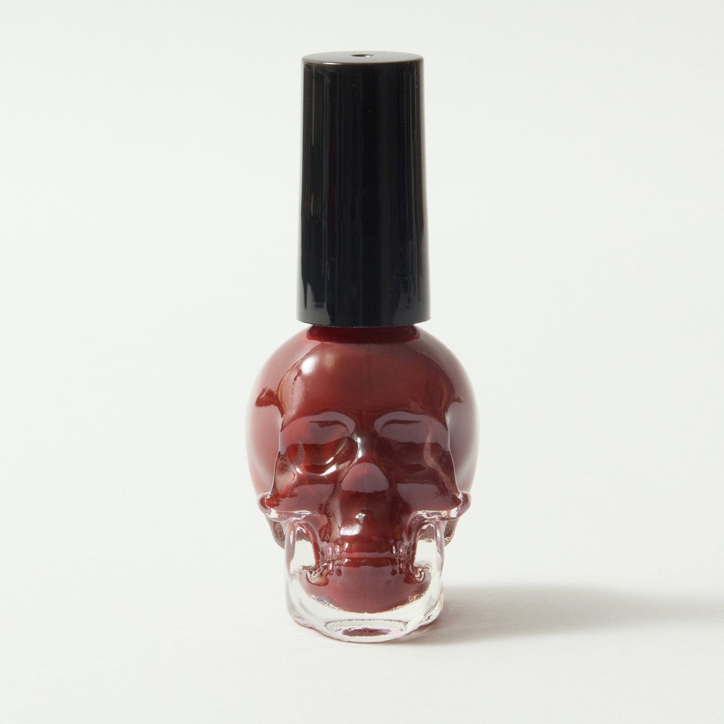 Gothica red nail varnish in a skull bottle, on a white background.