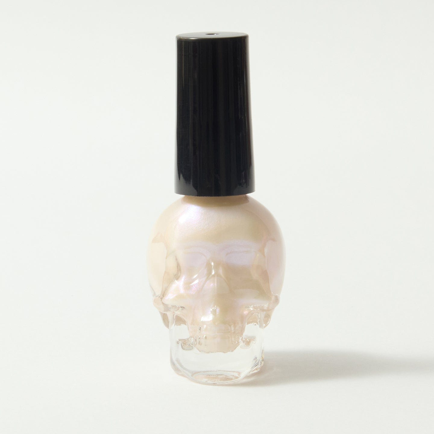 Gothica white nail varnish in a skull bottle, on a white background.