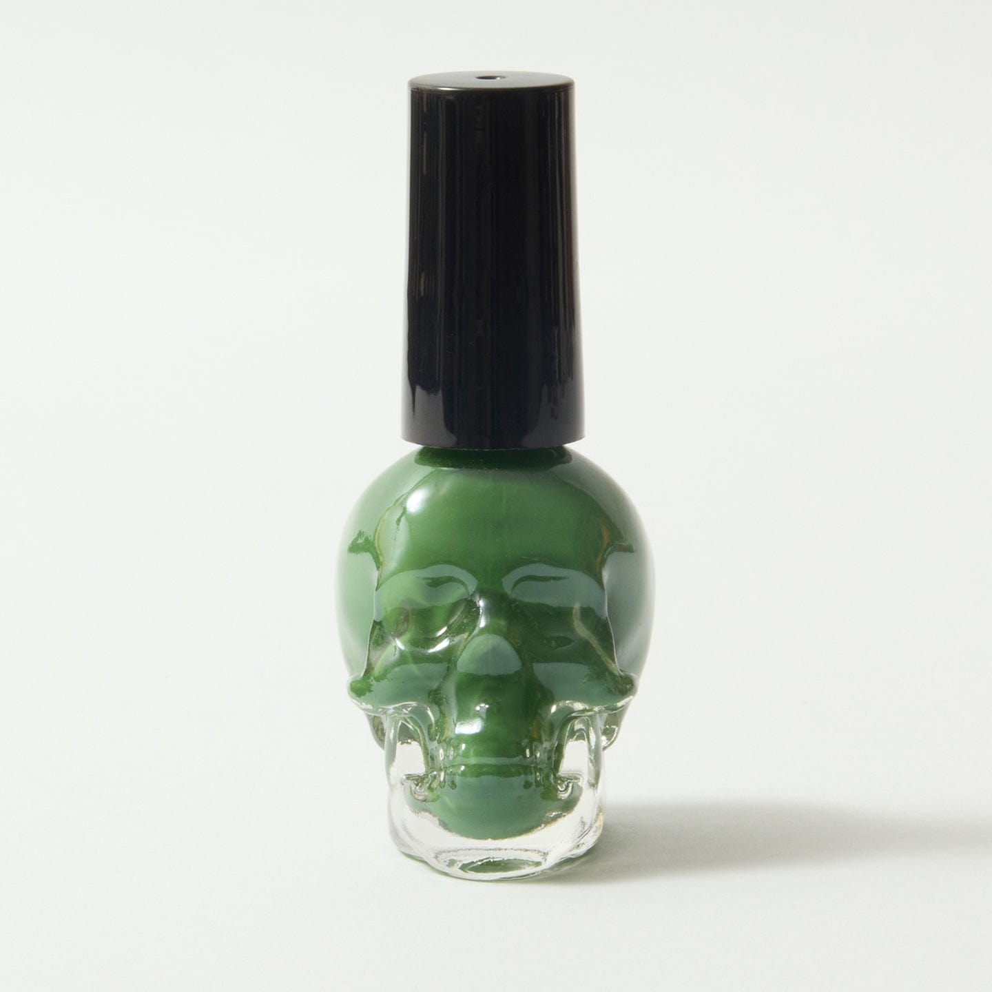 Gothica green nail varnish in a skull bottle, on a white background.